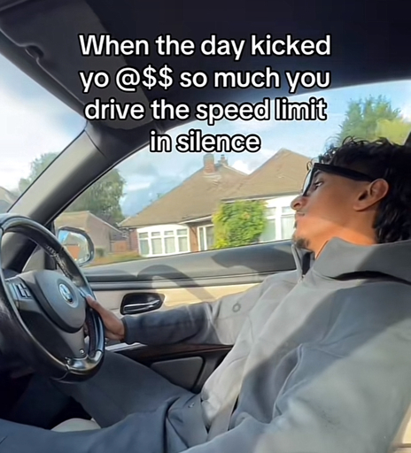 A person driving in their car with the caption “ When the day kicked yo @$$ so much you drive the speed limit in silence”